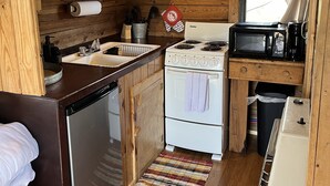 Une cuisine de taille réduite avec des murs en bois, une cuisinière, un four à micro-ondes et un évier.