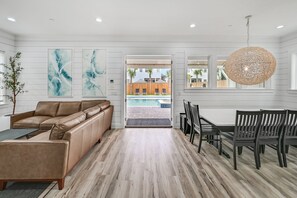 A modern living room with a sofa, dining table, chairs, and artwork on the walls.