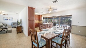 A spacious dining area with a wooden table set for six, surrounded by chairs with patterned cushions.
