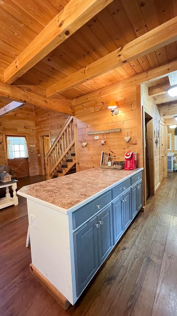 A wooden cabin interior with a kitchen island, blue cabinets, and a staircase leading to a lofted area. - Spend Fall Break at Rustic Star- Fiber Wifi! - Callaway Gardens Pumpkin Fest! (Warm Springs)