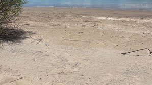 A beach with a clear sky and mountains in the background. - Firepit-Shade-Chairs-Dark Skies (Levan)