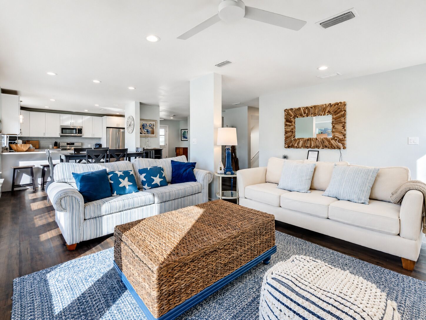 A modern living room with a sofa, a coffee table, and a dining area in the background.
