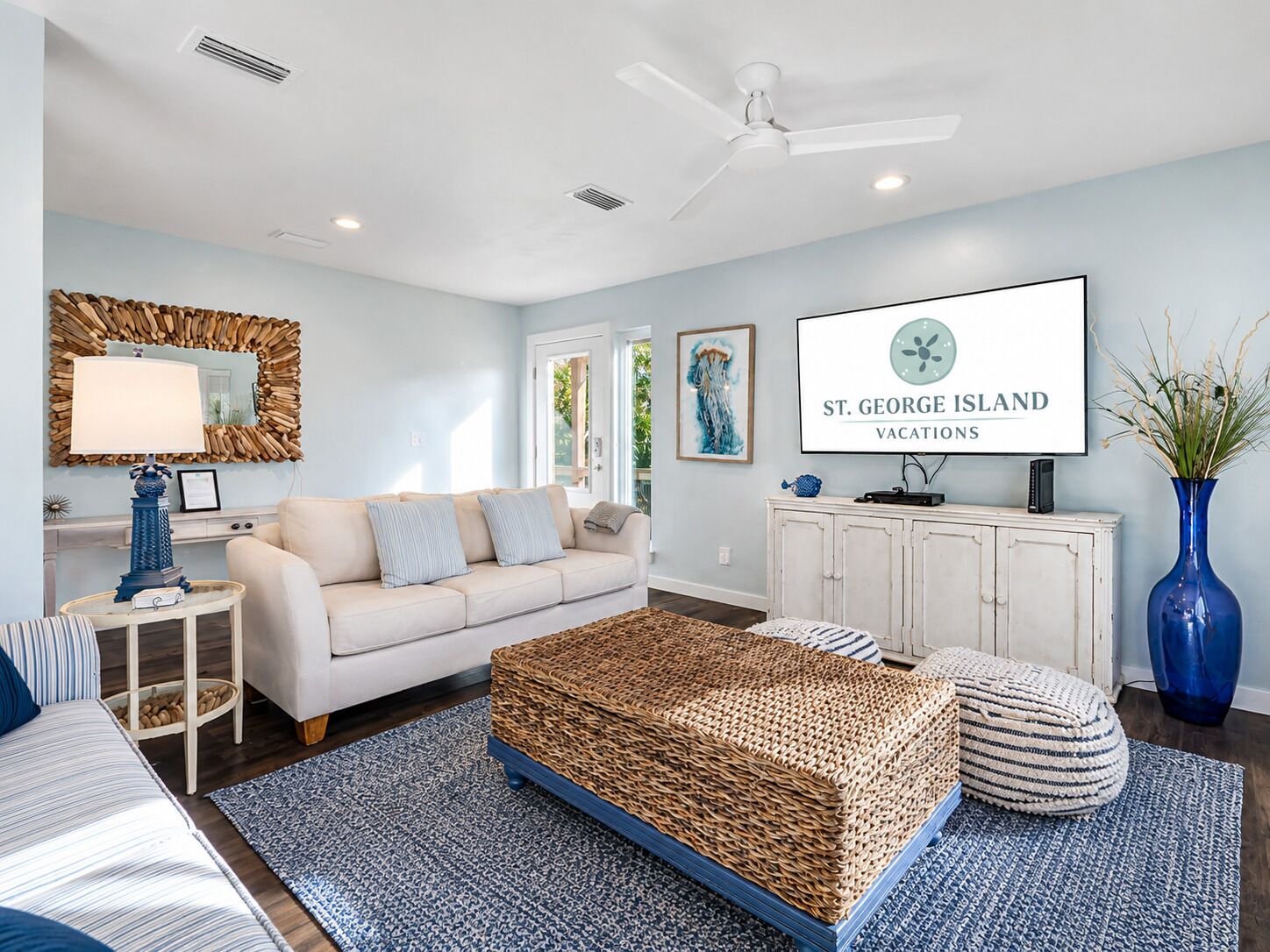 A living room with a sofa, a coffee table, a TV, and a large woven ottoman.