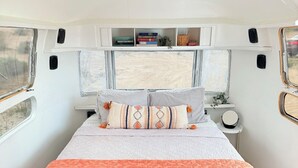 Een ruimtelijk RV-slaapkamer met een bed, nachtkastje en een raam.