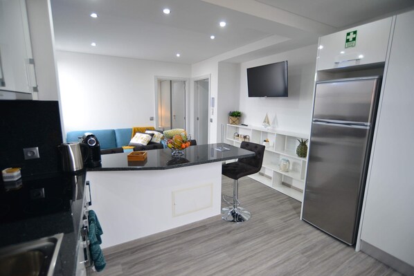 A modern kitchen with a central island, a built-in oven, and a stainless steel refrigerator. - Casas do Baleeiro - Whaler’s Houses (Machico)