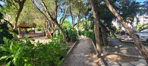 Stroll through lush gardens to a shaded retreat under a thatched roof.