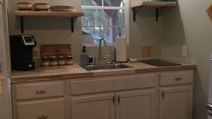 A kitchen with a window, a coffee maker, and a striped rug. - The Cranny @ Cookson —Tiny House Experience!!  Night,  week & monthly stays (Cookson)