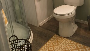 A bathroom with a glass shower enclosure, a toilet, and a small rug. - The Cranny @ Cookson —Tiny House Experience!!  Night,  week & monthly stays (Cookson)