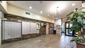 A reception area with a stone wall, a large plant, and a trash bin. - Private Rooms Downtown River Valley Condo Men only Non Smoking. (Edmonton)