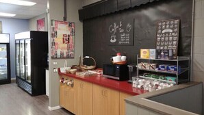 A coffee shop counter with a chalkboard menu, a refrigerator, and shelves with coffee cups and products. - Private Rooms Downtown River Valley Condo Men only Non Smoking. (Edmonton)