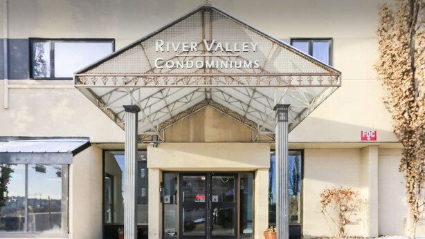 The entrance to River Valley Condominiums with a covered entrance and a sign above the doors. - Private Rooms Downtown River Valley Condo Men only Non Smoking. (Edmonton)