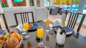 Un tavolo imbandito con piatti, bicchieri, una bottiglia di champagne e un cesto di frutta.