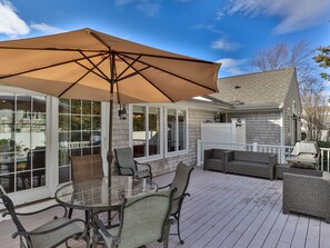 A covered outdoor patio with a glass table and chairs, a large umbrella, and a grill.