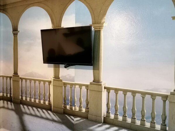 A balcony with a television mounted on the wall, balustrades, and a view of the sky. - Apartment in a rural house with a large garden 5 minutes from the beach (sales, colunga)