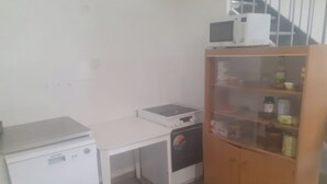 A compact kitchen with a microwave, a small refrigerator, a dishwasher, and a wooden cabinet with glass doors. - Great apartment! (Roques)