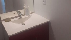 A bathroom with a white sink, a mirror, and a cabinet. - Great apartment! (Roques)
