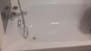 A bathroom with a bathtub, a showerhead, and a toilet. - Great apartment! (Roques)