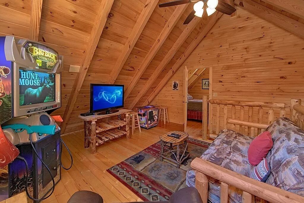 Un intérieur chaleureux de chalet en bois, avec une télévision, une console de jeux et un coin salon confortable.