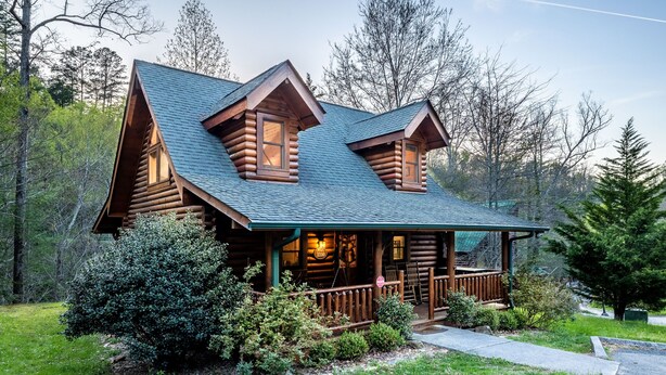 Een vakantiehuisje van hout met een veranda, schoorsteen en een klein terras.