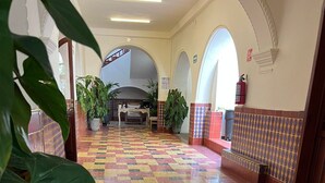 A spacious hallway with a checkered floor pattern, tiled walls, and large green plants. - Hotel Catedral Cuernavaca (Cuernavaca)