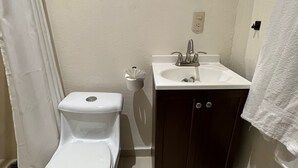 A bathroom with a toilet, sink, mirror, and a trash bin. - Hotel Catedral Cuernavaca (Cuernavaca)