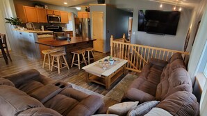 A cozy living area with a large sofa, a coffee table, and a kitchen in the background. - Stage Stop Suite (Piedmont)