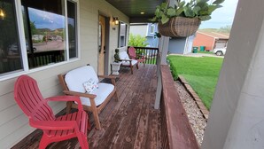 A wooden deck with two red Adirondack chairs and a white sofa. - Stage Stop Suite (Piedmont)