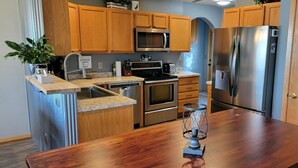 A modern kitchen with wooden cabinets, stainless steel appliances, and a wooden countertop. - Stage Stop Suite (Piedmont)