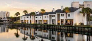 A waterfront hotel with multiple white buildings, each with a balcony and a view of the water. - Destin Townhome Steps from Beach & Pool (Destin)