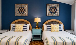 A double bed with a striped bedspread, two nightstands, a lamp, and decorative wall art. - Destin Townhome Steps from Beach & Pool (Destin)