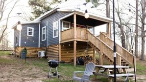 Una cabaña con terraza, una fogata y asientos exteriores.