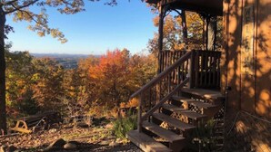 A wooden cabin with a porch and a staircase leading up to it, surrounded by autumn foliage. - MOUNTAIN TOP Lodge with Gorgeous Panoramic View, Hot Tub, Pool Table & Fireplace (Sevierville)