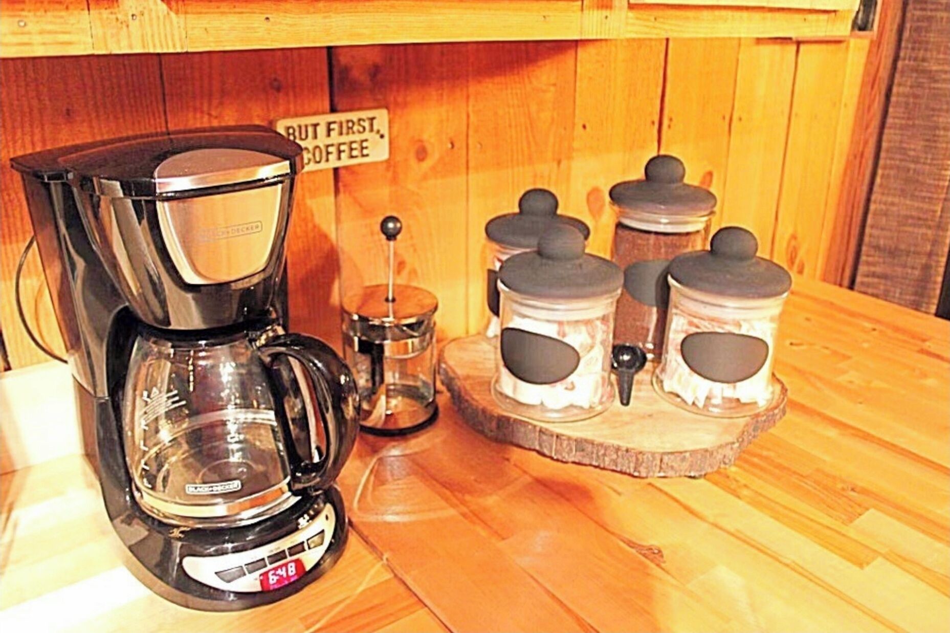 A coffee maker, a scale, and three containers on a wooden table.