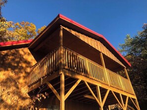 A wooden deck with a red roof, surrounded by trees. - MOUNTAIN TOP Lodge with Gorgeous Panoramic View, Hot Tub, Pool Table & Fireplace (Sevierville)