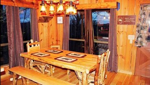 A rustic wooden dining area with a large table, benches, and hanging lanterns. - MOUNTAIN TOP Lodge with Gorgeous Panoramic View, Hot Tub, Pool Table & Fireplace (Sevierville)