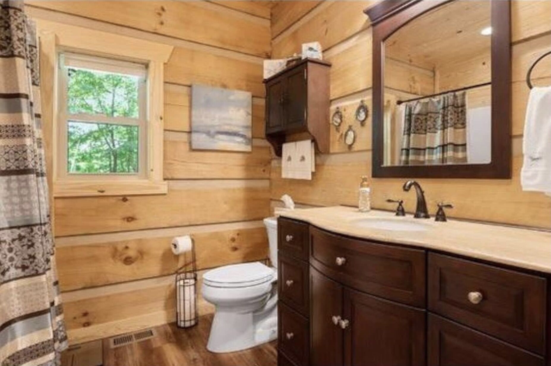 A wooden cabin bathroom with a toilet, sink, and cabinet.