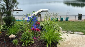 A lakeside garden with a dock, chairs, and a variety of plants. - Always East Lake-  all sports lake, on Little Hart Lake, swim, kayak, fishing (Twin Lake)
