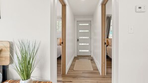 A hallway with wooden flooring, a white door with frosted glass panels, and a small rug on the floor. - Always East Lake-  all sports lake, on Little Hart Lake, swim, kayak, fishing (Twin Lake)