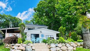 A two-story house with a stone staircase leading to the front door, surrounded by a well-maintained lawn and a variety of plants. - Always East Lake-  all sports lake, on Little Hart Lake, swim, kayak, fishing (Twin Lake)