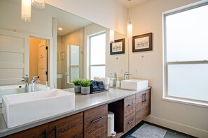 Une salle de bain moderne avec deux vasques, des meubles en bois et un grand miroir.