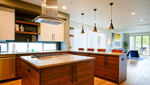 Una cocina moderna con armarios de madera, una isla central e iluminación colgante.