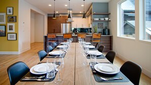 Un comedor con una larga mesa de madera dispuesta para una comida, rodeado de sillas.