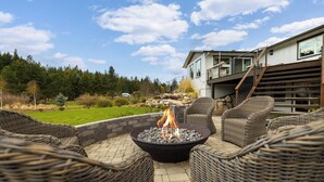 An outdoor seating area with wicker chairs and a central fire pit. - 3 Acres Remodeled Home With Hot Tub Walking Distance to Beach! Garden & Fire Pit (Coeur d Alene)
