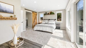 A bedroom with a large bed, a sliding door, a window, and a view of the outdoors. - 3 Acres Remodeled Home With Hot Tub Walking Distance to Beach! Garden & Fire Pit (Coeur d Alene)