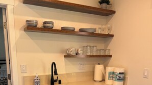 A compact kitchen with white cabinets, a stainless steel dishwasher, and wooden shelves above the counter. - Cozy 1bd/1bath Apartment Unit in Downtown Vancouver (Vancouver)