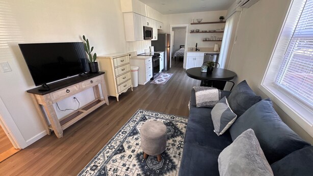 A modern living room with a flat-screen TV, a dark sofa with cushions, a patterned rug, and a wooden coffee table. - Cozy 1bd/1bath Apartment Unit in Downtown Vancouver (Vancouver)