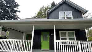A two-story house with a porch, a green door, and a white railing. - Cozy 1bd/1bath Apartment Unit in Downtown Vancouver (Vancouver)