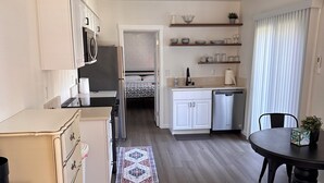 A compact kitchen with white cabinets, a microwave, and a refrigerator. There is a dining area with a table and chairs, and a small rug on the floor. - Cozy 1bd/1bath Apartment Unit in Downtown Vancouver (Vancouver)