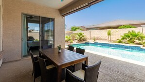 Un espace extérieur aménagé avec une piscine, une table et des chaises.