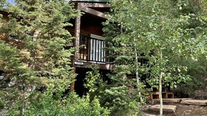 A wooden cabin with a balcony, surrounded by dense forest. - Cozy Mountain Paradise (Kamas)